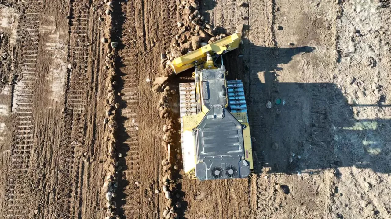 Overhead drone view of a tracked machine with a rock rake working graded ground